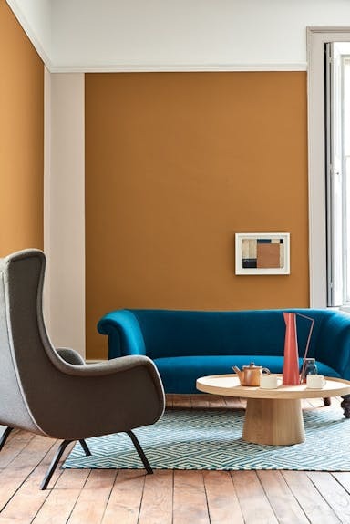 Oker muur met petrolblauwe sofa